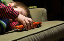 Child playing with toy car on a sofa