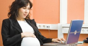 Pregnant woman seated in front of a laptop computer