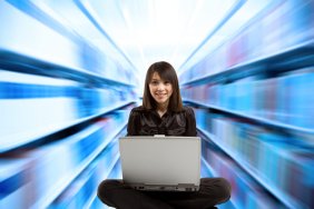 Young woman seated facing a laptop, with shelves of books zooming by on both sides